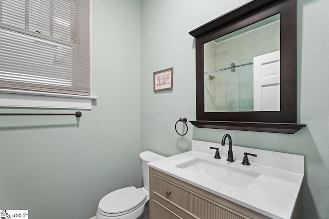 bathroom featuring toilet, vanity, and a shower