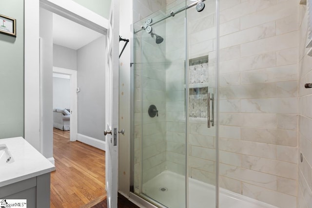 full bathroom with a shower stall, baseboards, vanity, and wood finished floors