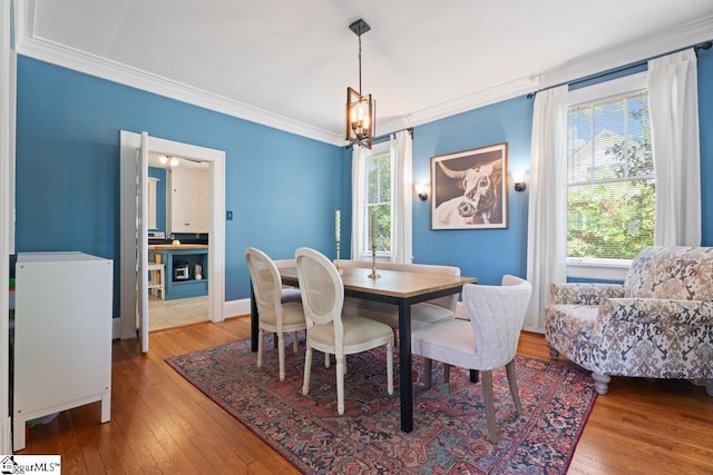 dining space with an inviting chandelier, crown molding, hardwood / wood-style floors, and a healthy amount of sunlight