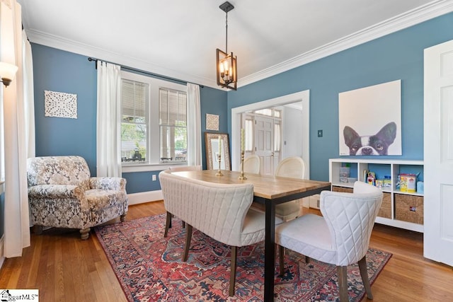 dining space featuring baseboards, wood finished floors, an inviting chandelier, and crown molding