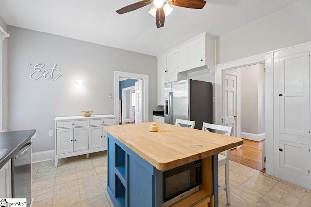 kitchen featuring white cabinets, stainless steel appliances, open shelves, a ceiling fan, and wood counters