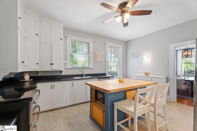 kitchen featuring stainless steel electric range oven, a wealth of natural light, a sink, and butcher block countertops