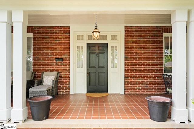 view of exterior entry featuring covered porch and brick siding
