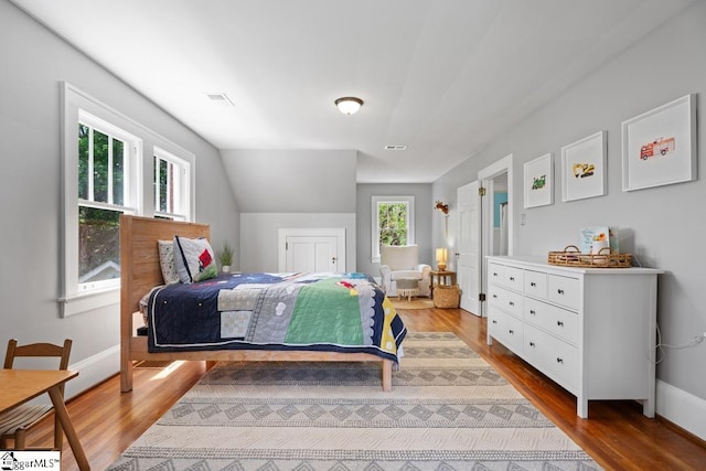 bedroom with baseboards, wood finished floors, and visible vents