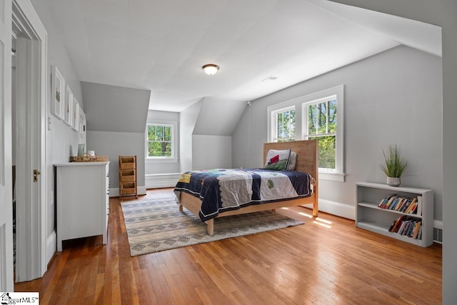 bedroom featuring hardwood / wood-style floors, vaulted ceiling, visible vents, and multiple windows