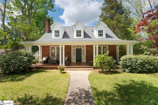 view of front of home with a shingled roof, a front lawn, a chimney, and brick siding