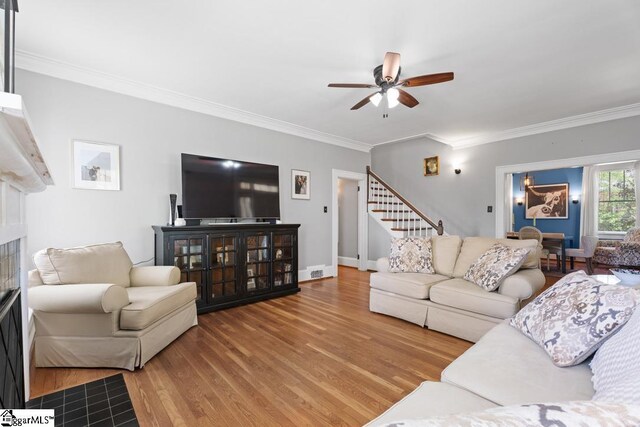 living room with baseboards, a ceiling fan, wood finished floors, stairway, and ornamental molding