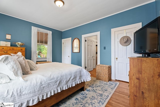 bedroom with ornamental molding and wood finished floors