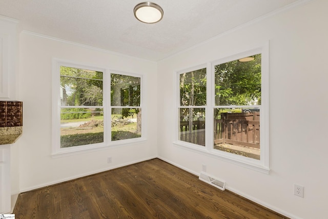 spare room featuring dark wood finished floors, visible vents, crown molding, and baseboards