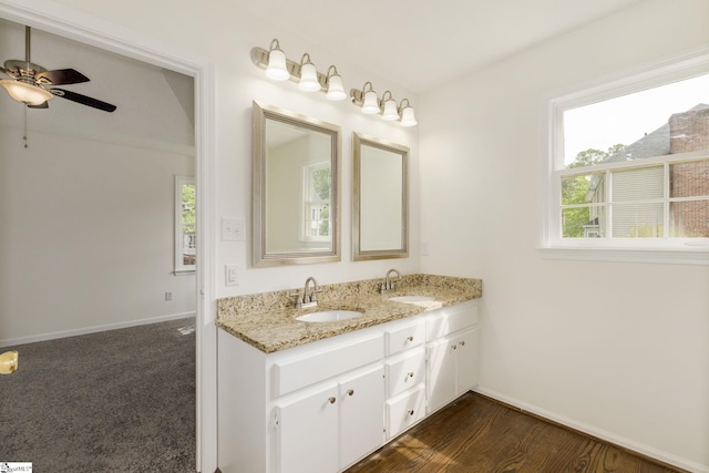 bathroom with ceiling fan, baseboards, a sink, and double vanity