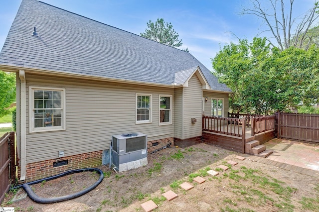 rear view of property with crawl space, a deck, fence, cooling unit, and roof with shingles