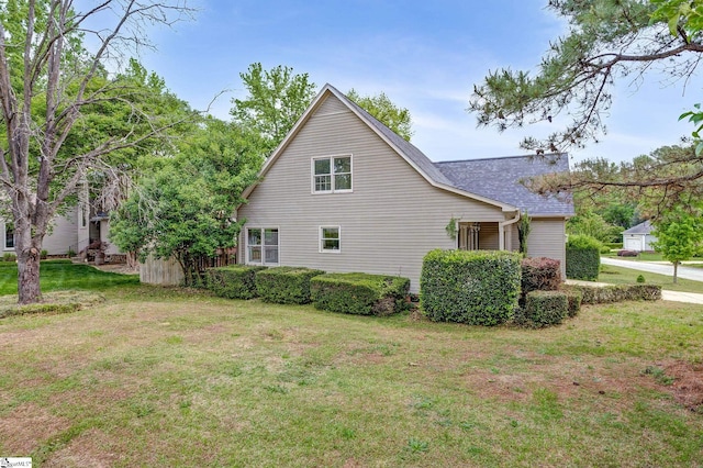 view of side of property featuring a lawn and roof with shingles