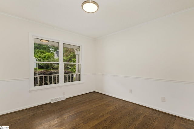 empty room featuring baseboards, visible vents, dark wood-style floors, and crown molding