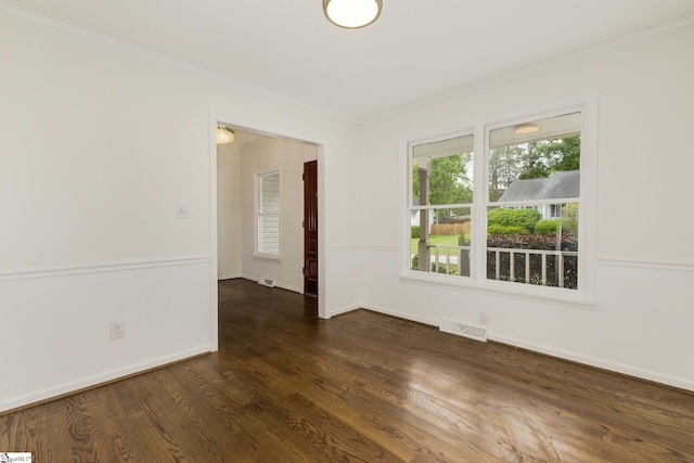 empty room with baseboards, visible vents, ornamental molding, and dark wood-style flooring