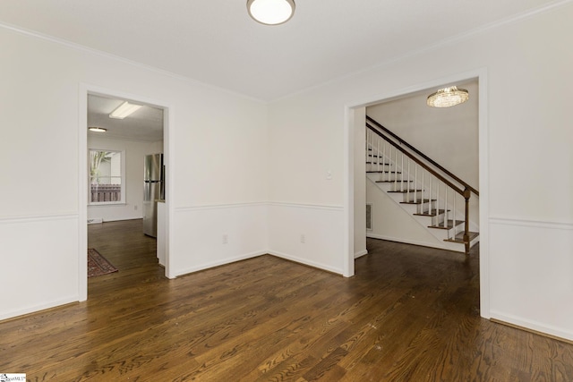 unfurnished room with wood finished floors, visible vents, crown molding, and stairway