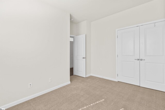 unfurnished bedroom with carpet floors, a closet, and baseboards