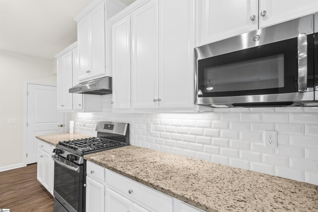 kitchen featuring white cabinets, stainless steel appliances, tasteful backsplash, light stone countertops, and under cabinet range hood