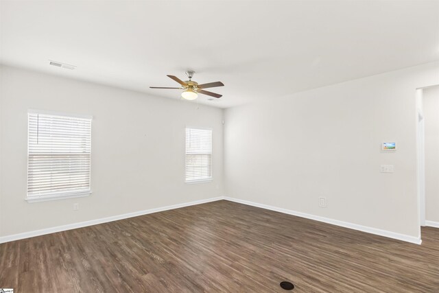 spare room featuring baseboards, visible vents, dark wood-style floors, and ceiling fan