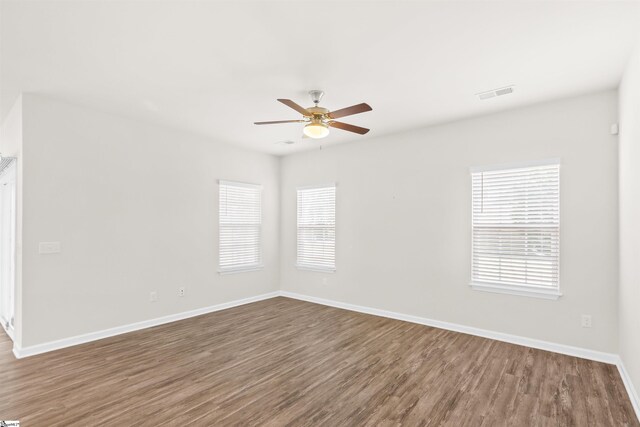 unfurnished room with wood finished floors, baseboards, a ceiling fan, and visible vents