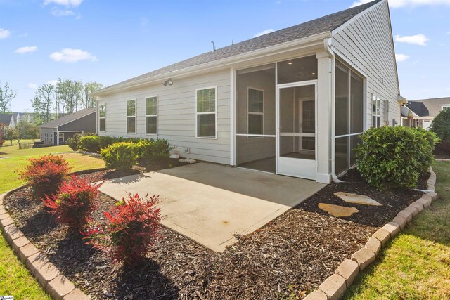 rear view of property featuring a yard, a sunroom, and a patio