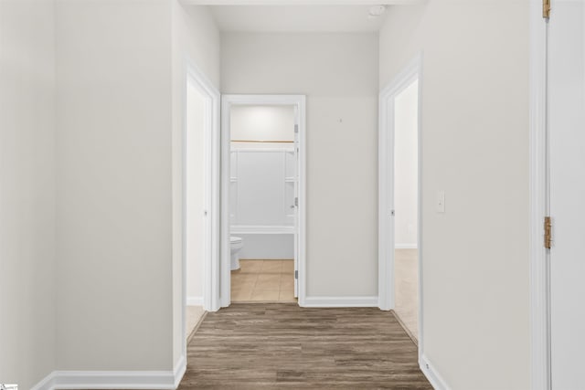 hall with baseboards and wood finished floors