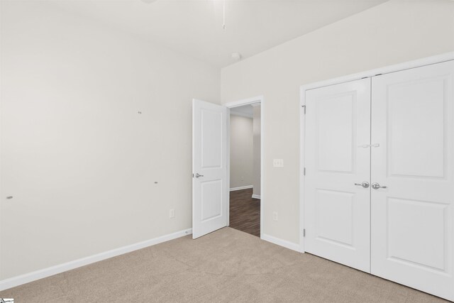 unfurnished bedroom with baseboards, carpet floors, and a closet