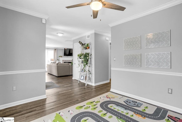 interior space featuring wood finished floors, visible vents, ornamental molding, baseboards, and ceiling fan