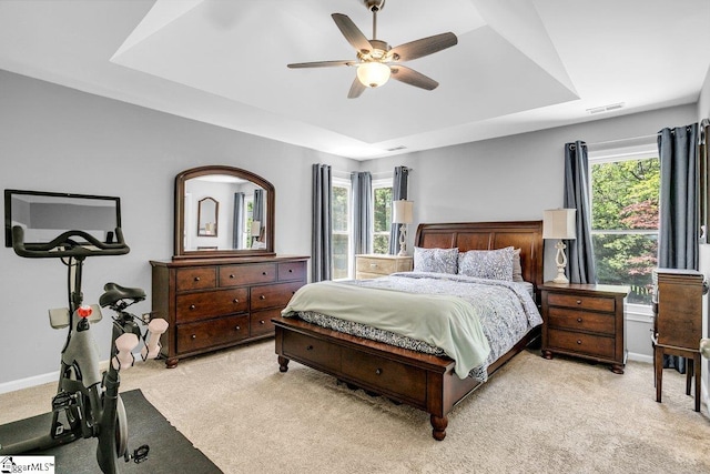 bedroom featuring a raised ceiling, visible vents, multiple windows, and light carpet