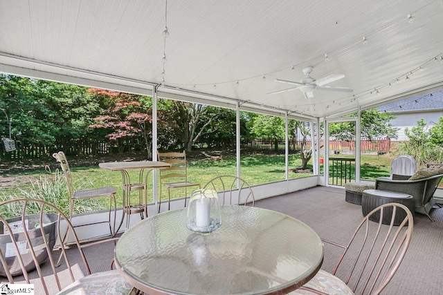 sunroom / solarium with outdoor dining area and a ceiling fan