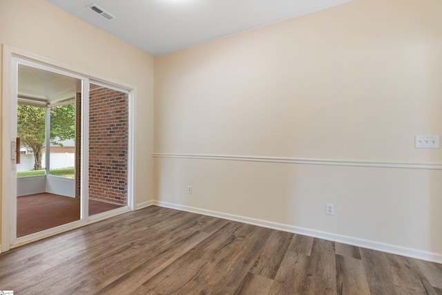 spare room featuring baseboards, wood finished floors, and visible vents