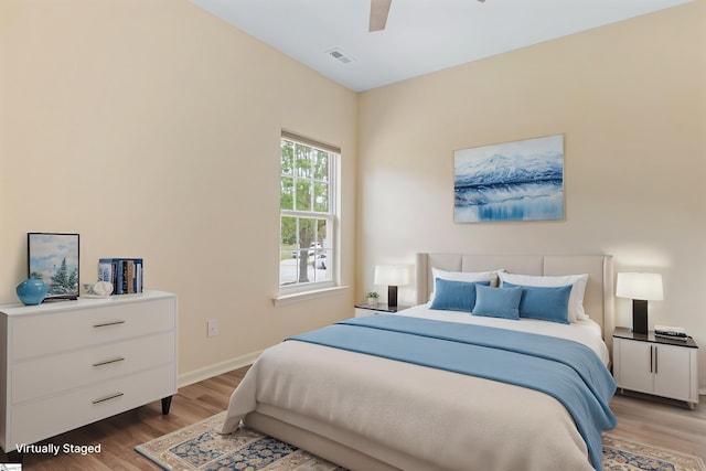 bedroom featuring baseboards, wood finished floors, visible vents, and ceiling fan