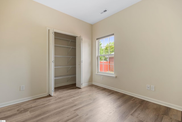 unfurnished bedroom with a closet, light wood-style floors, visible vents, and baseboards