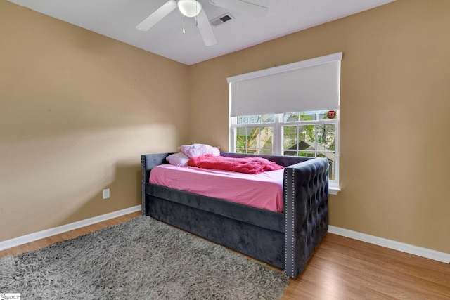 bedroom with baseboards, wood finished floors, visible vents, and ceiling fan