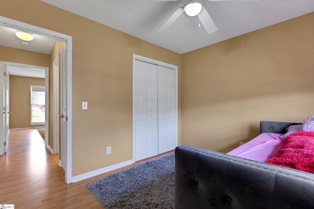 bedroom featuring baseboards, a ceiling fan, light wood finished floors, and a closet