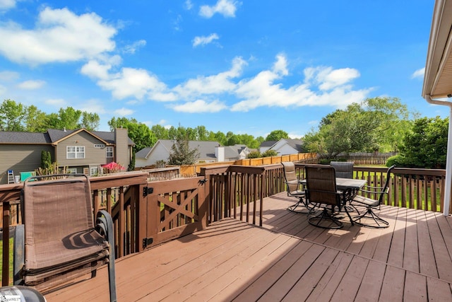 wooden deck featuring a residential view, outdoor dining space, and a fenced backyard
