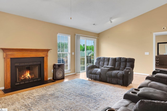 living room featuring a fireplace with flush hearth, baseboards, vaulted ceiling, and visible vents