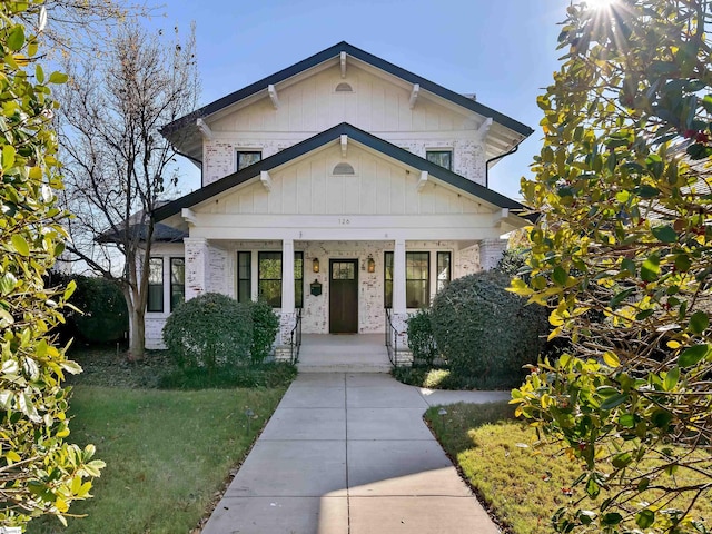 view of front of property featuring brick siding, a porch, and a front yard