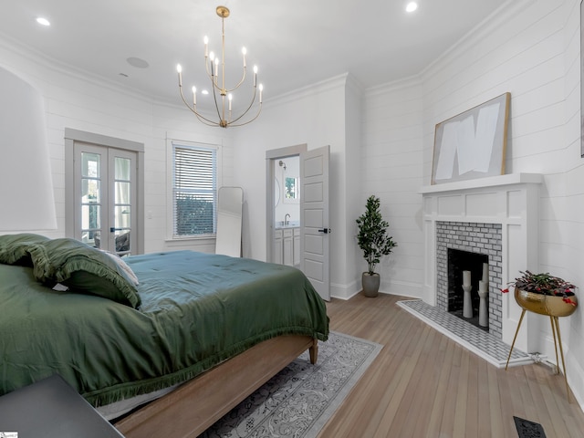 bedroom with light wood finished floors, french doors, visible vents, a brick fireplace, and ornamental molding
