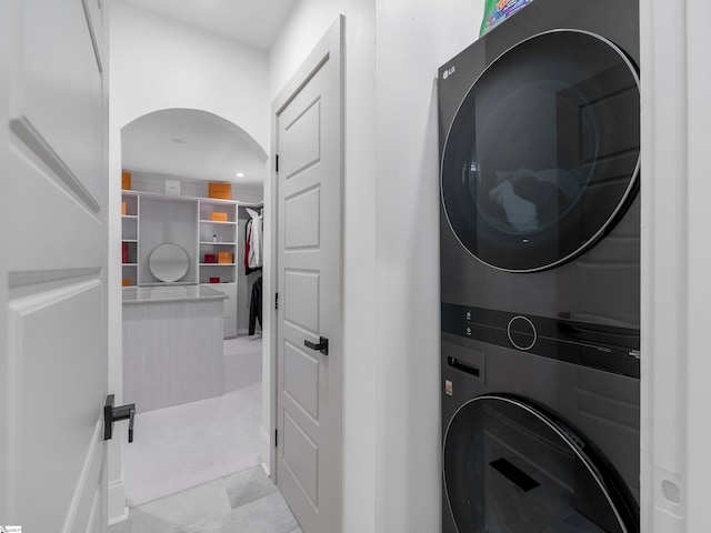 laundry room with arched walkways, stacked washer and dryer, recessed lighting, and laundry area