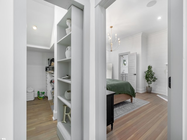 corridor with a notable chandelier, baseboards, ornamental molding, and light wood finished floors
