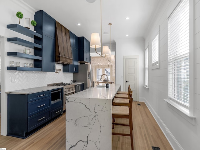 kitchen featuring stainless steel appliances, open shelves, a sink, light wood-type flooring, and blue cabinetry