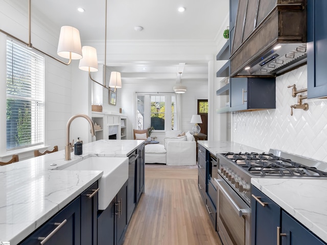 kitchen with blue cabinets, a sink, tasteful backsplash, custom exhaust hood, and appliances with stainless steel finishes