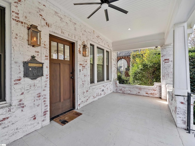 property entrance with brick siding, a ceiling fan, and covered porch