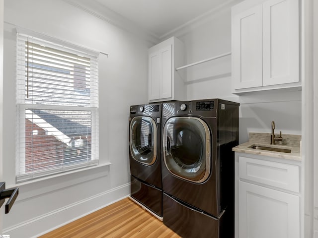 clothes washing area with crown molding, a sink, light wood-type flooring, cabinet space, and washing machine and dryer