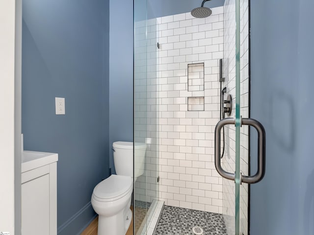 bathroom featuring a shower stall, toilet, and vanity