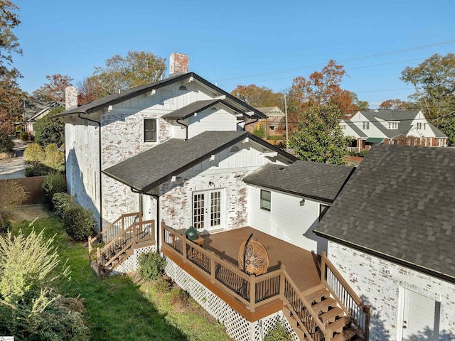 rear view of house with stairway, a chimney, a deck, a shingled roof, and french doors