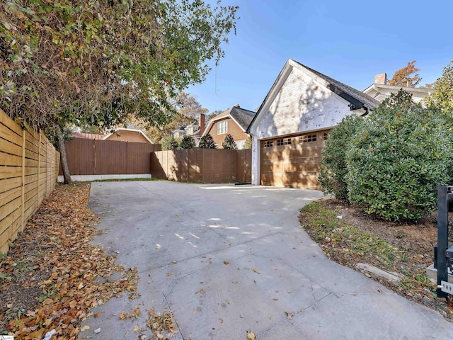exterior space with driveway, fence private yard, brick siding, and a garage