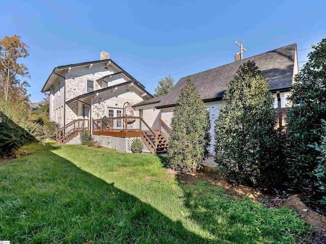 rear view of house featuring a chimney, stairs, a yard, a wooden deck, and stone siding