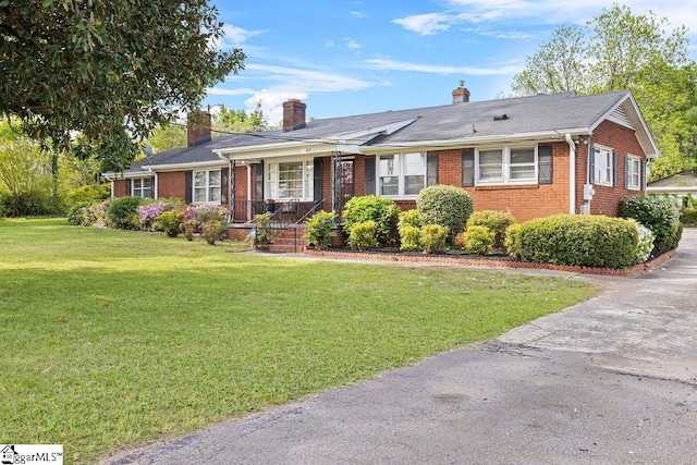 single story home with a chimney, a front yard, and brick siding