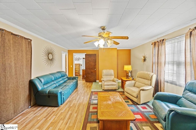 living area featuring wood finished floors, ceiling fan, and crown molding
